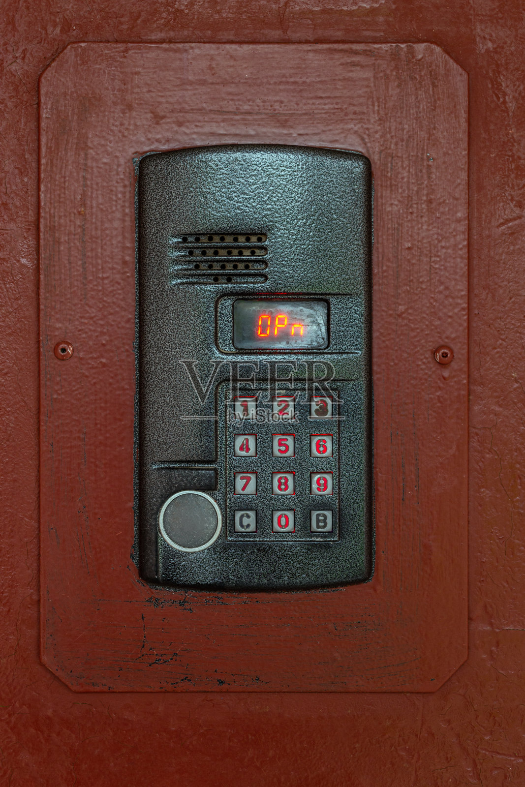 一个旧漆棕色钢表面的对讲机，配有键盘，数字显示器和射频识别传感器，用于呼叫特写照片摄影图片