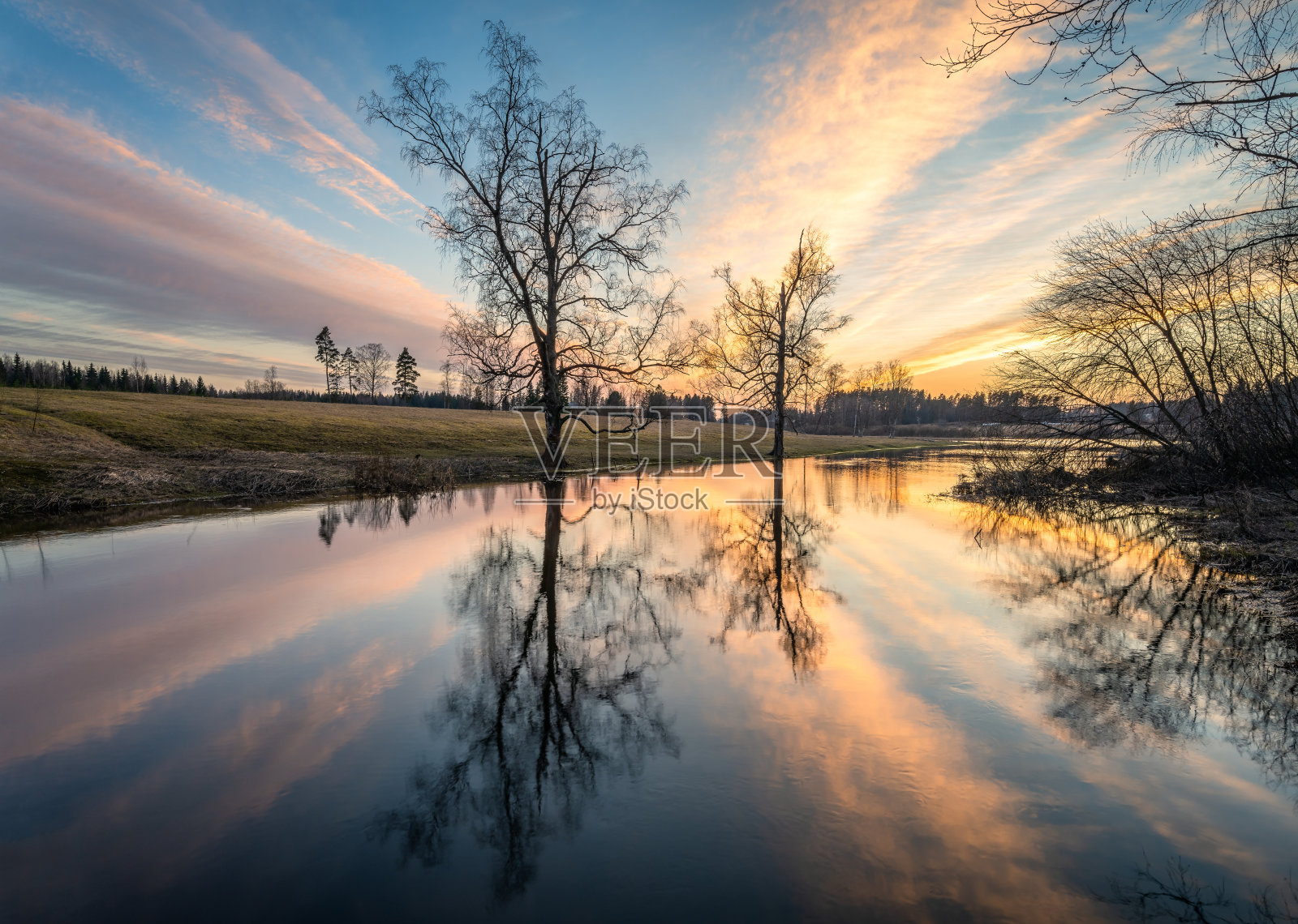 美丽的晚霞与宁静的风景与树木的倒影和阳光在春天傍晚在芬兰河照片摄影图片