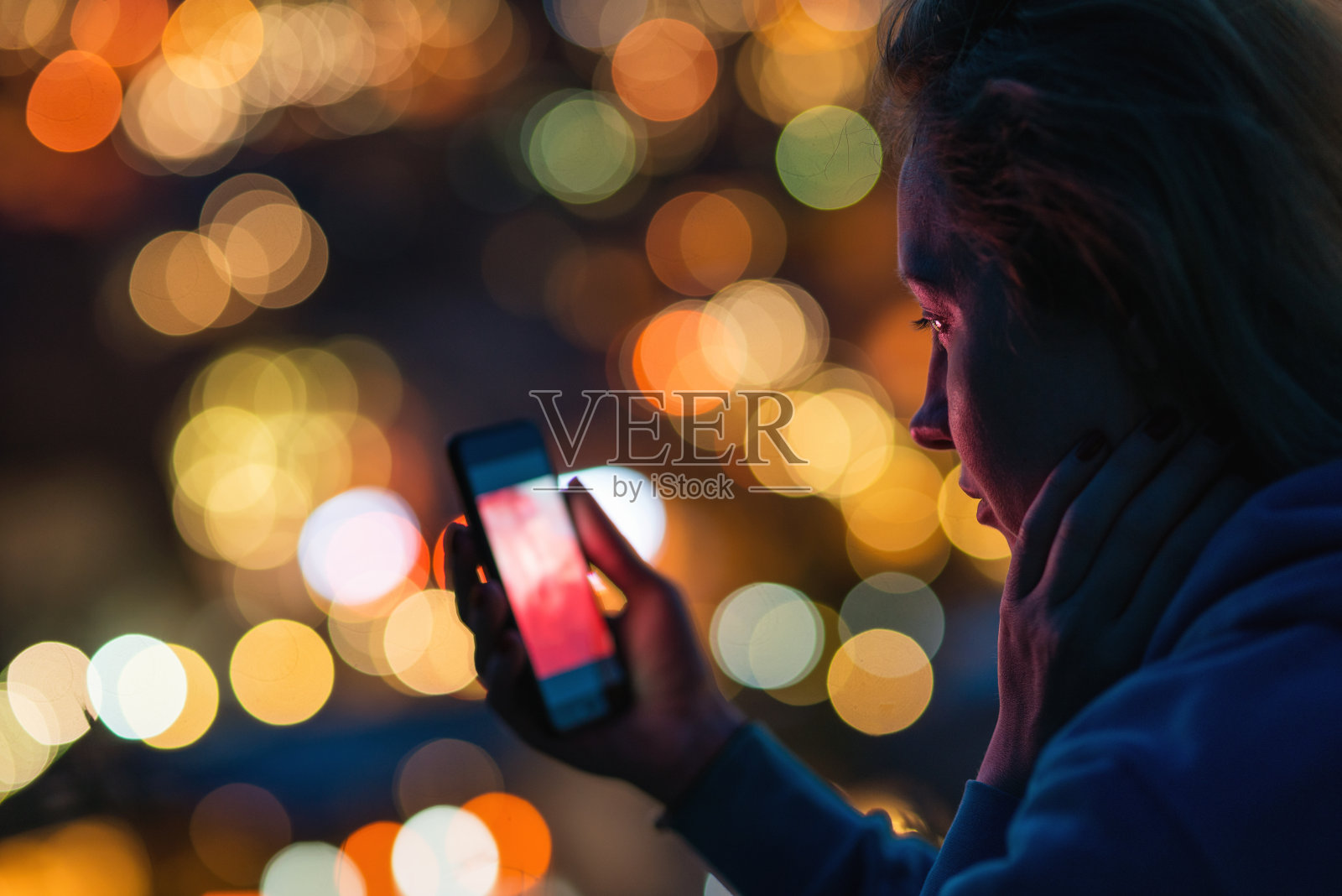 女人在户外用智能手机，把城市灯光调散在背景上照片摄影图片