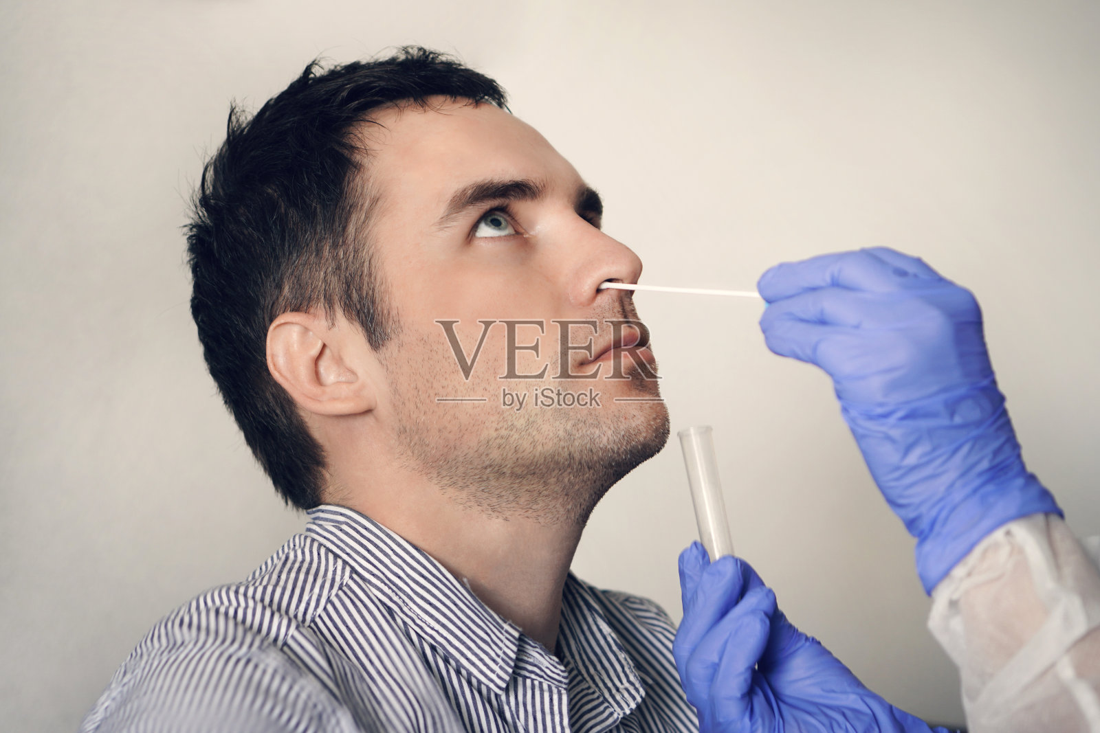 医生从男性鼻子提取鼻黏液样本，进行呼吸道病毒测试。检查耳鼻喉科的鼻腔。照片摄影图片