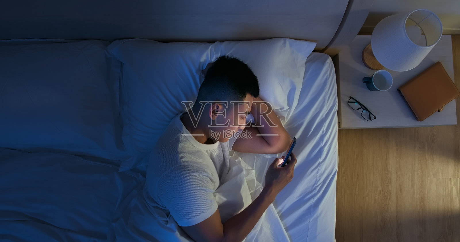 男人在床上使用智能手机照片摄影图片