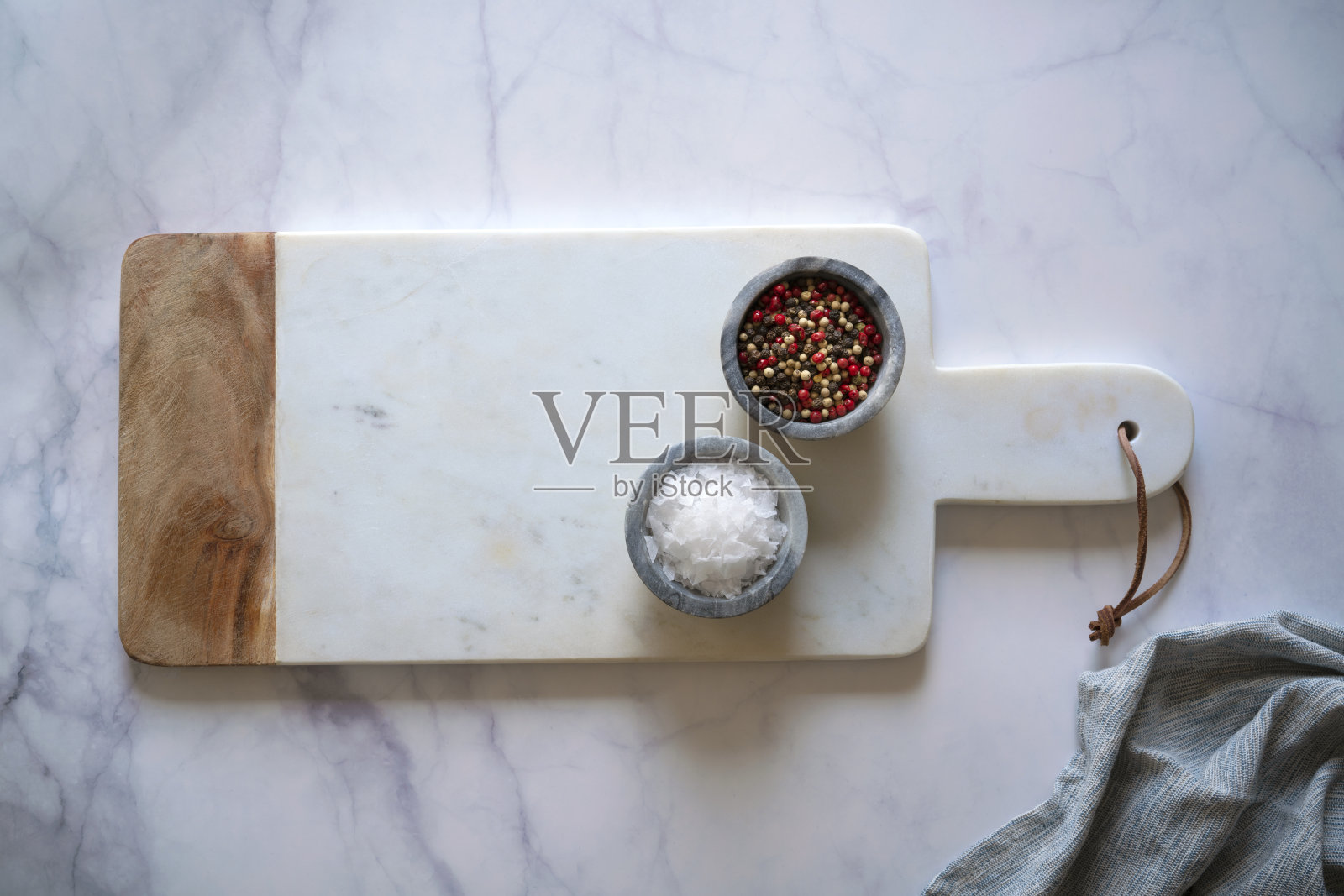 白色大理石砧板放在白色大理石柜台上，加盐和胡椒调味料照片摄影图片