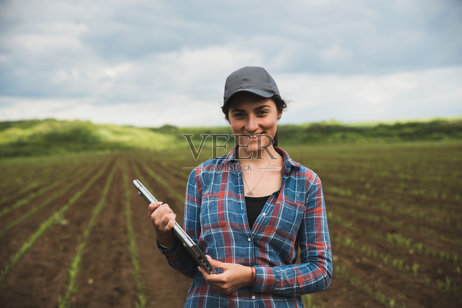 一个微笑的年轻农学家的肖像与笔记本电脑在玉米田照片摄影图片