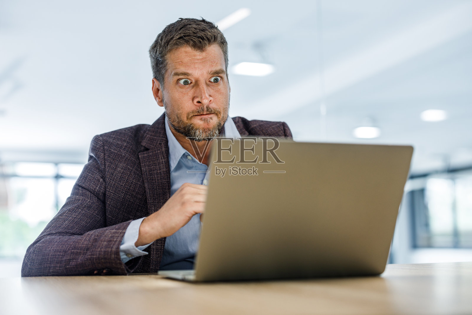 中年男性企业家在办公室通过笔记本电脑进行视频通话时感到沮丧。照片摄影图片