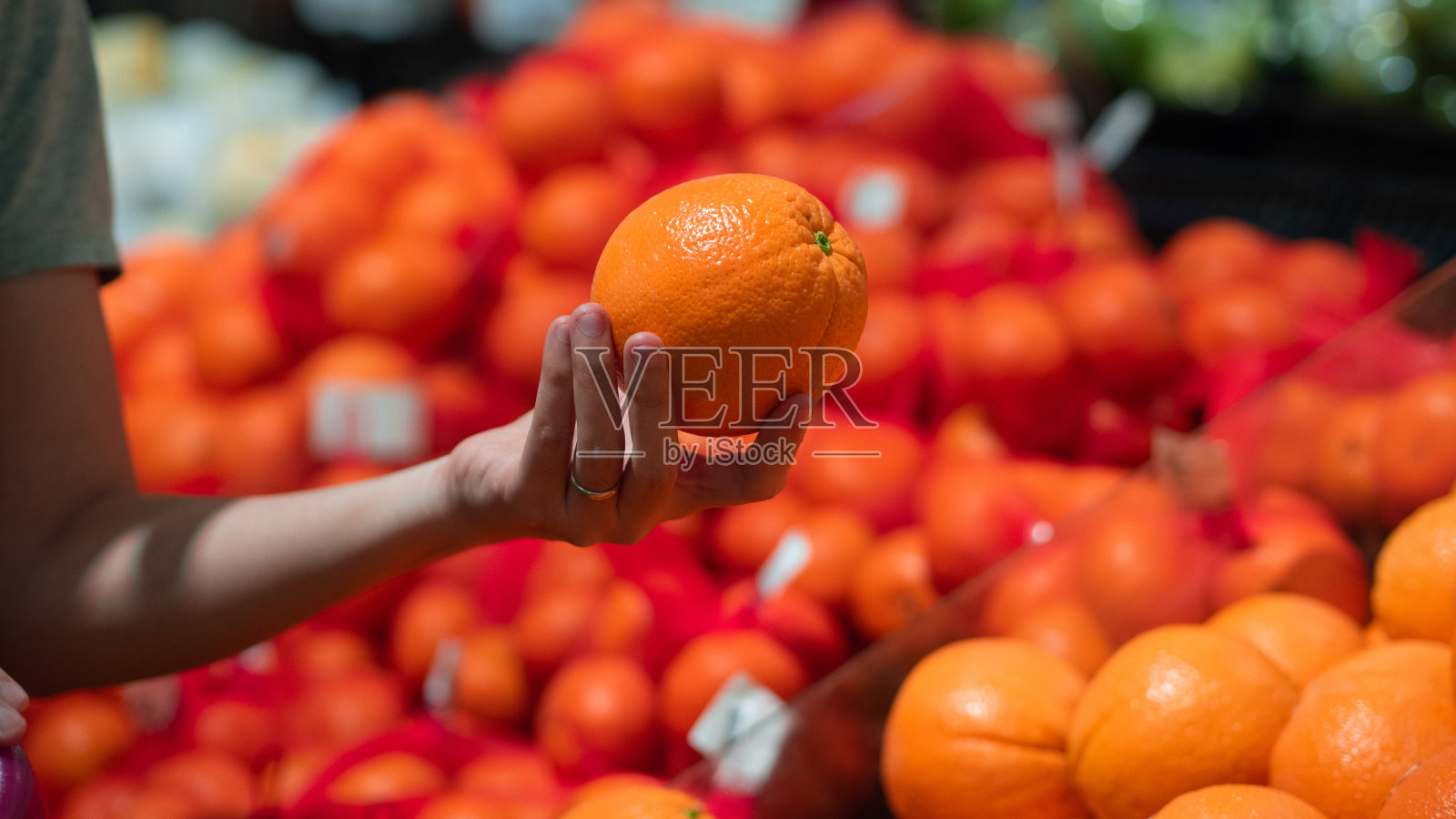 手握桔子与橙色背景的近视图。夏天的颜色。照片摄影图片