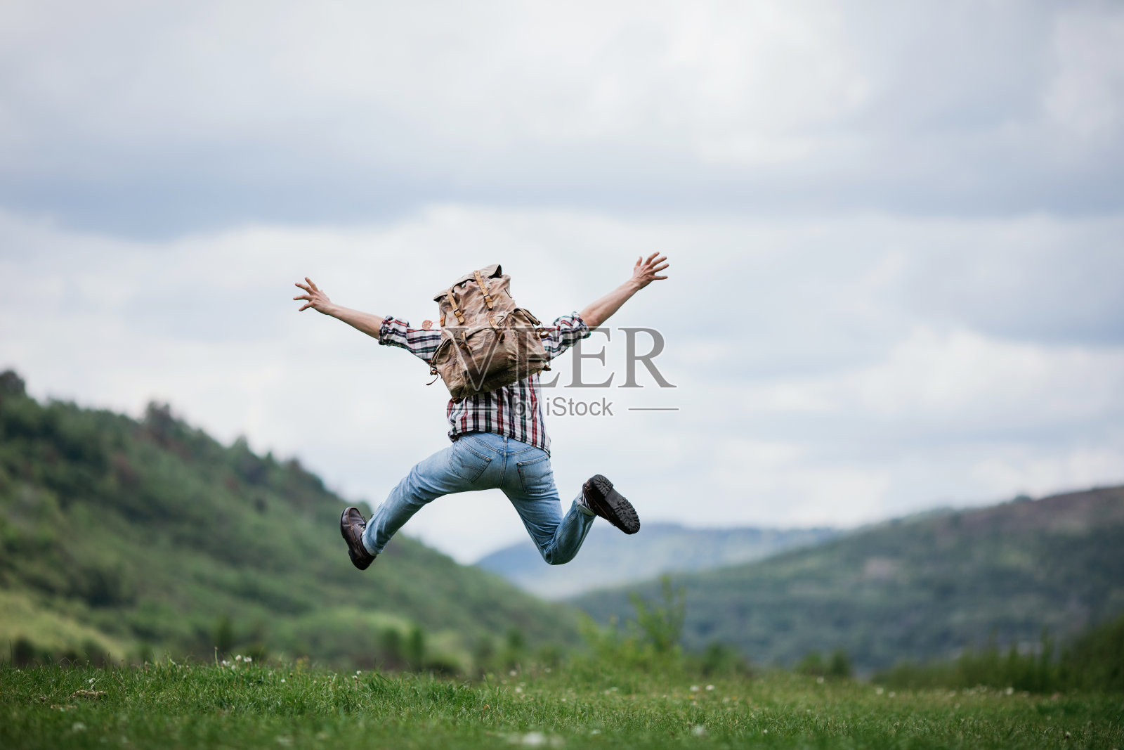 快乐的男人旅行者背包跳跃在山区活跃的暑假，旅游概念照片摄影图片