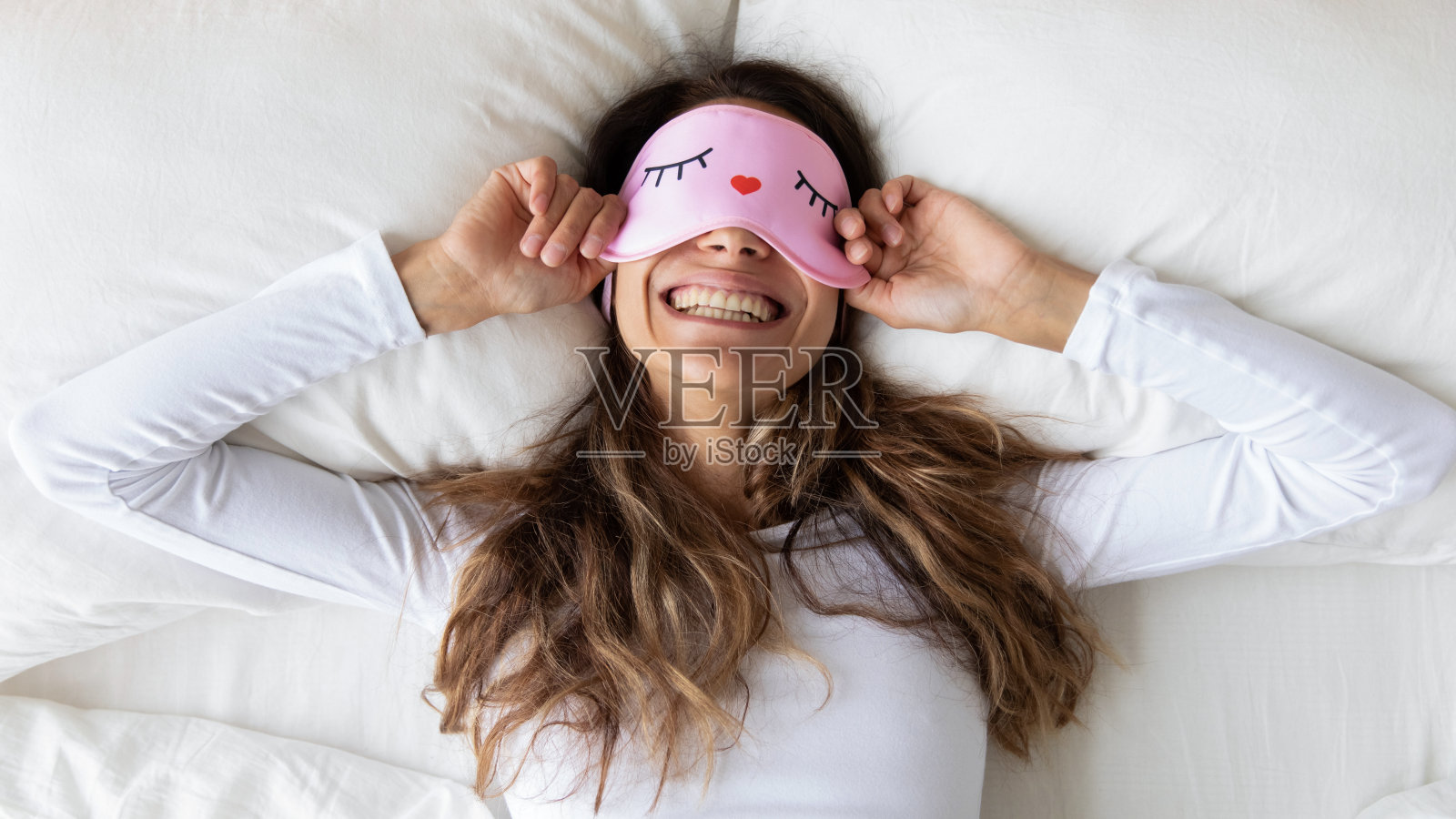 顶视图快乐的女人戴着滑稽的睡眠面具享受早晨照片摄影图片