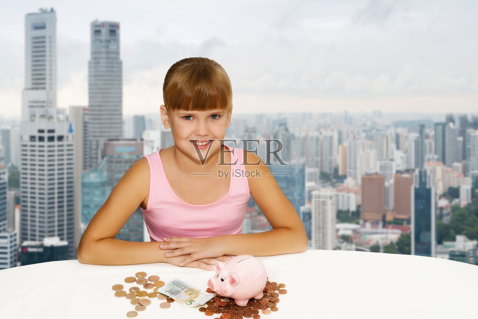 可爱的小女孩用硬币和储蓄罐放在桌子上以城市为背景。为教育基金存钱。人，孩子，经营理念照片摄影图片