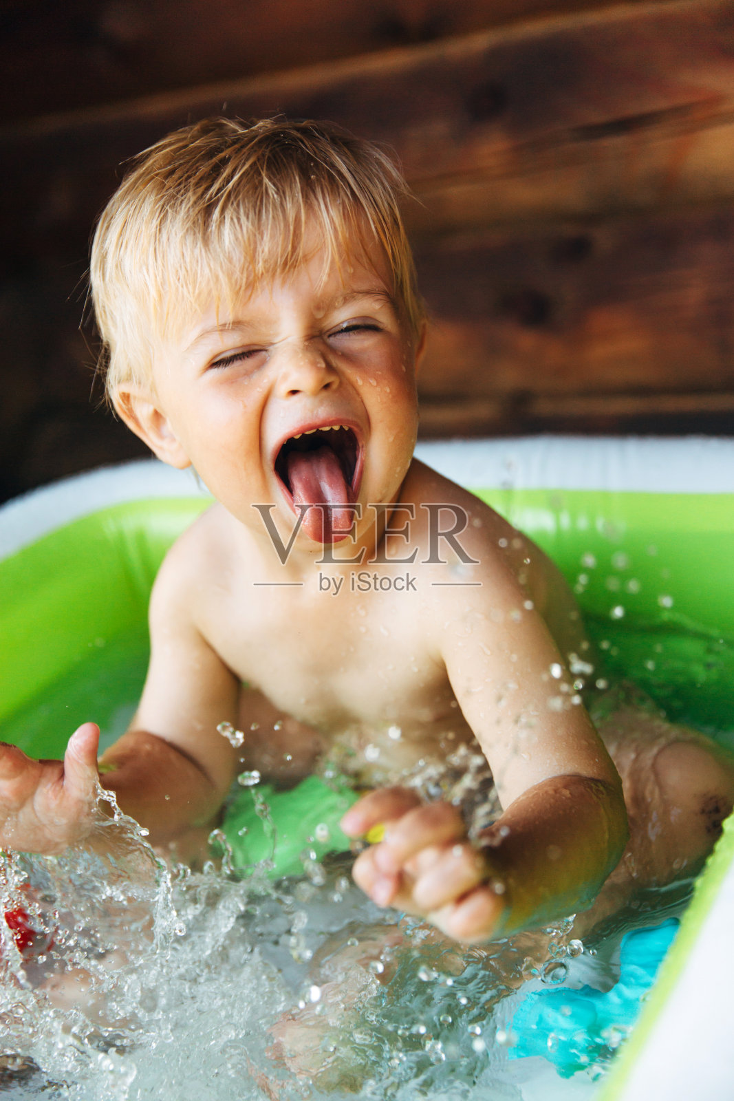 蹒跚学步的男孩在充气游泳池的乐趣照片摄影图片
