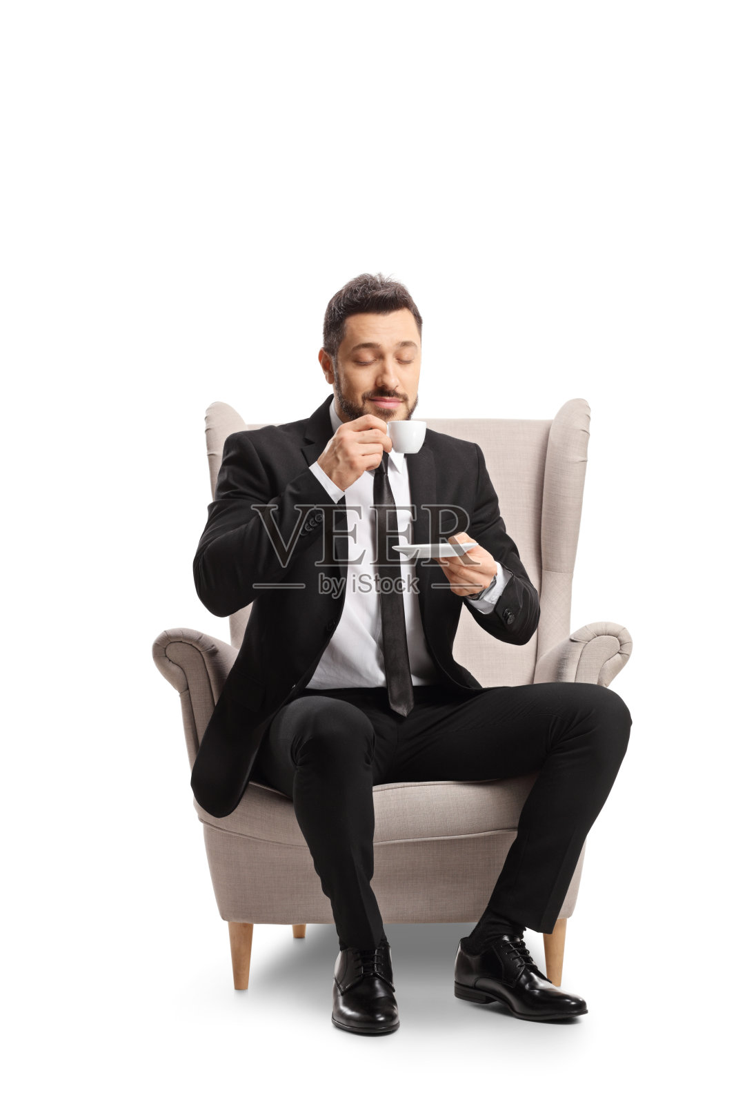 商人坐在扶手椅上，喝着一杯浓缩咖啡照片摄影图片