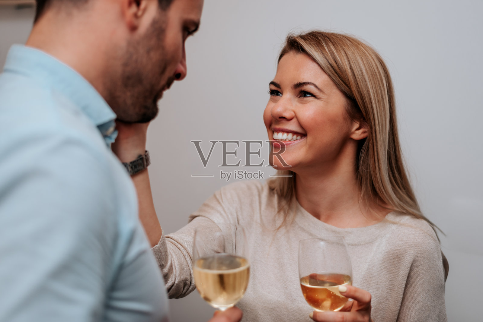 微笑的夫妇喝着白葡萄酒，拥抱在一起。特写镜头。照片摄影图片