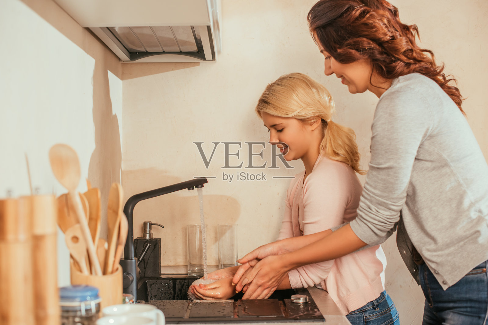 微笑的母亲和孩子在厨房洗手的侧视图照片摄影图片
