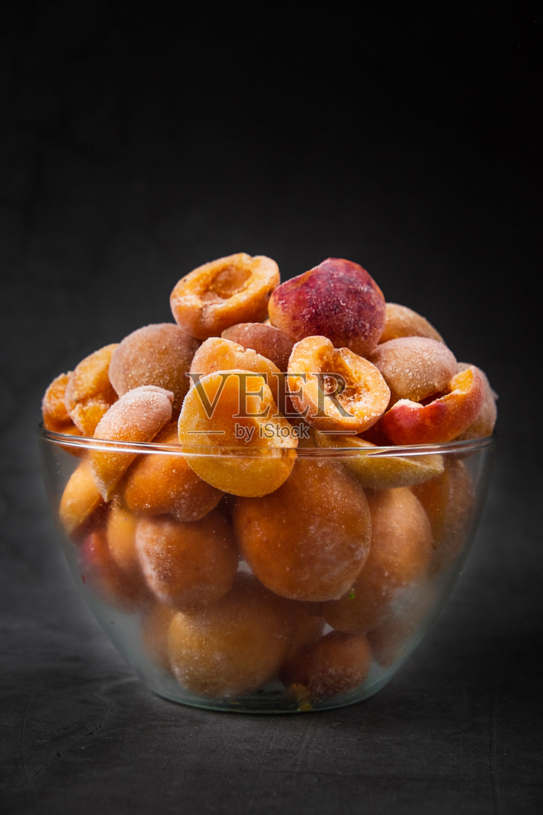 冰冻的杏子桃子覆盖在薄冰在一个玻璃球与白霜在灰色的背景。保存维生素。冰冻水果产品。冬天食物保藏。冰箱里的冷餐。快速冻结照片摄影图片