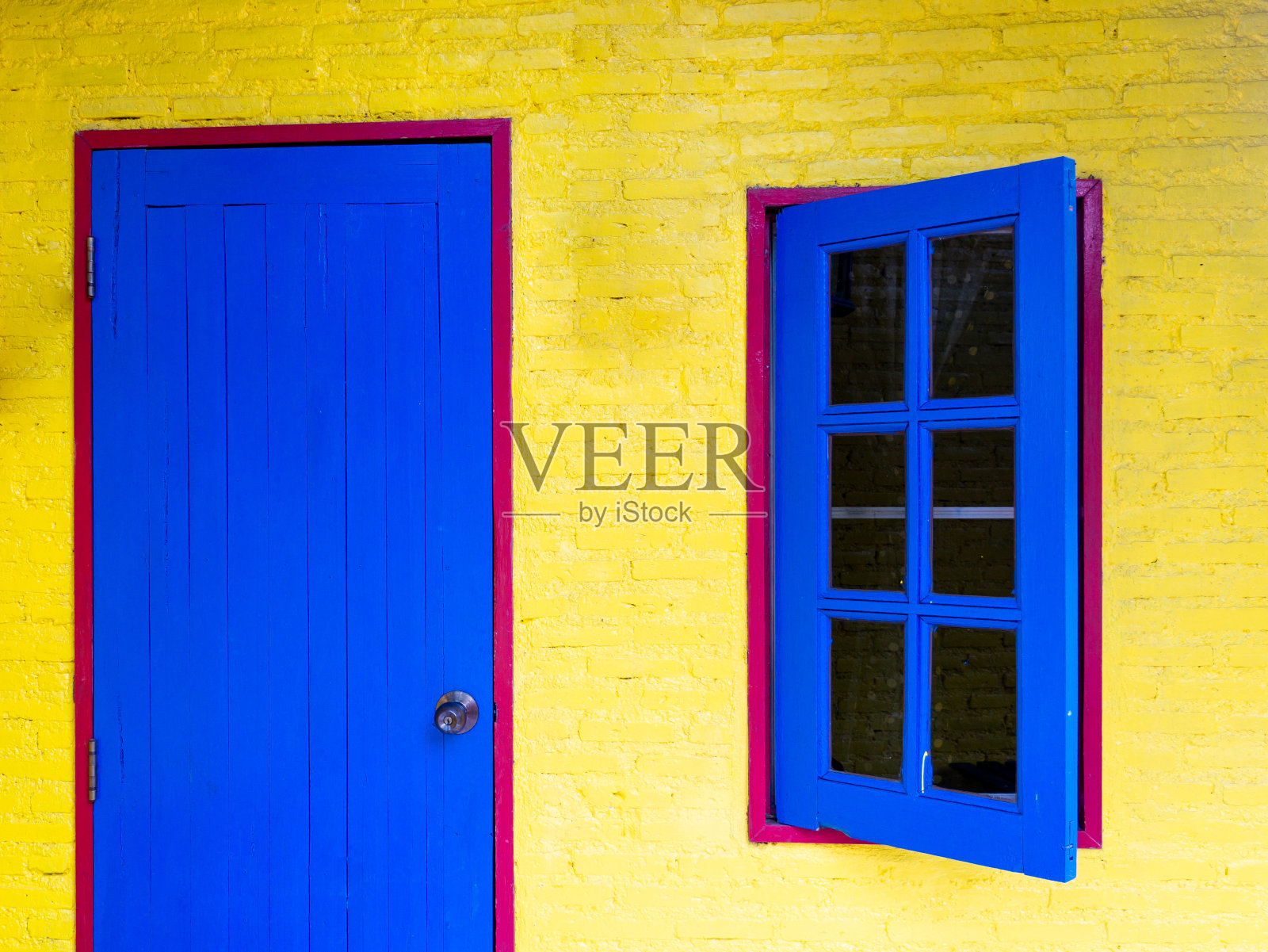 黄色墙中红色框架上的蓝色木窗和门照片摄影图片