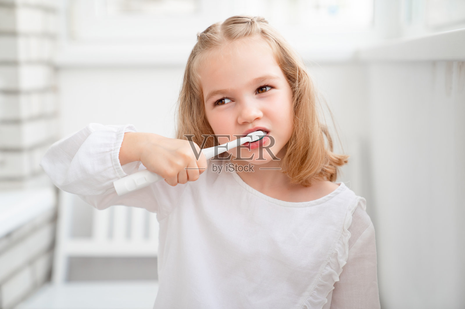 有趣的女孩用电动牙刷刷牙照片摄影图片