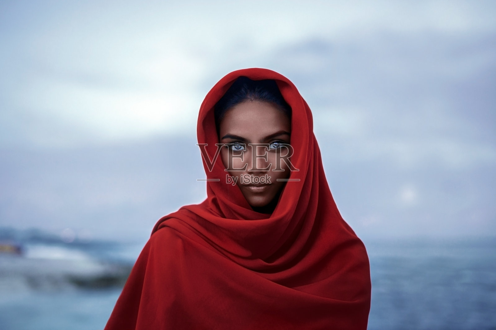 美丽的印度女人与红色的paranja和蓝色的眼睛在黄昏照片摄影图片