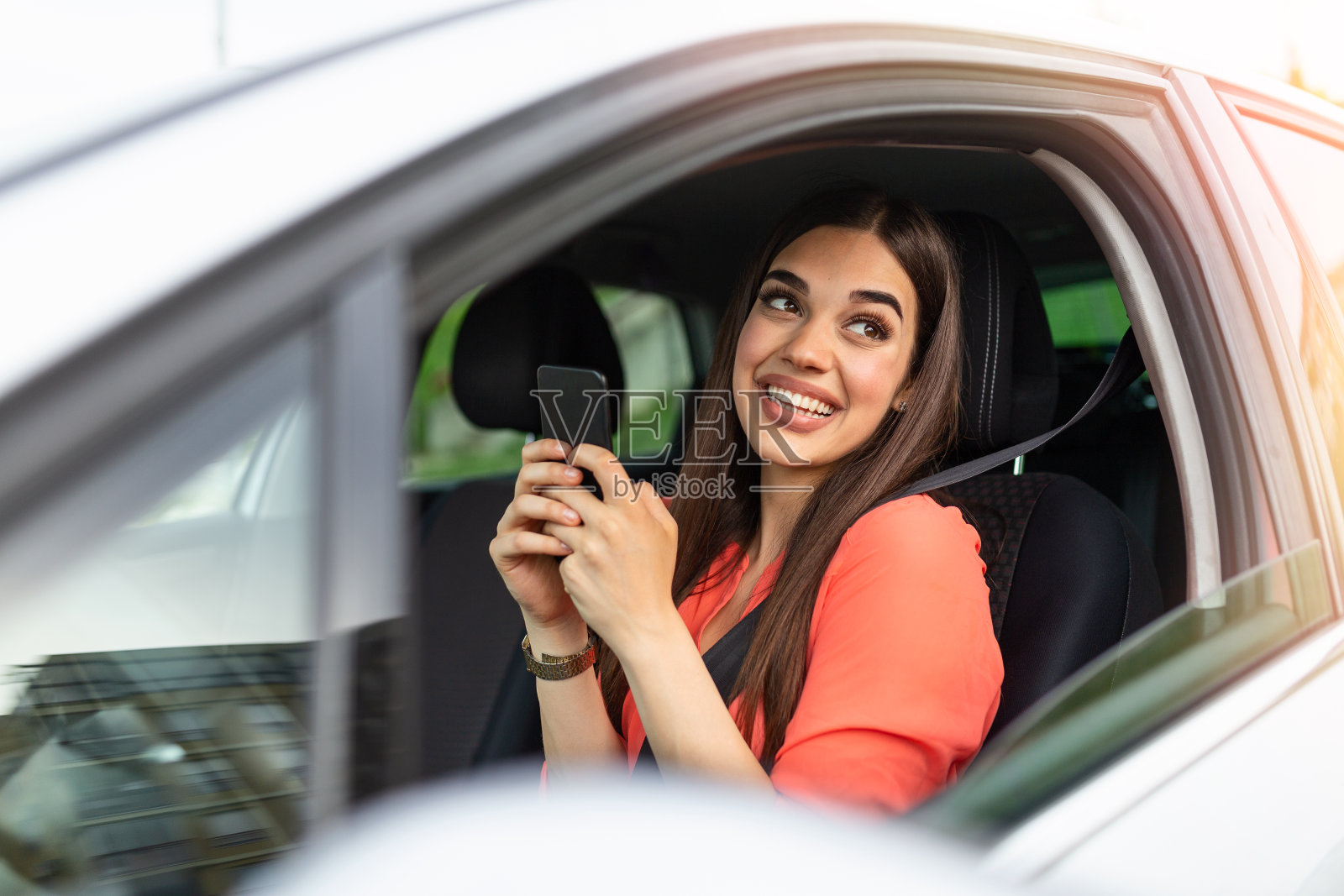 漂亮的年轻女子微笑和使用手机触摸车内屏幕旅行。现代概念的搜索和联系朋友时，你离开。智能手机的日常使用照片摄影图片