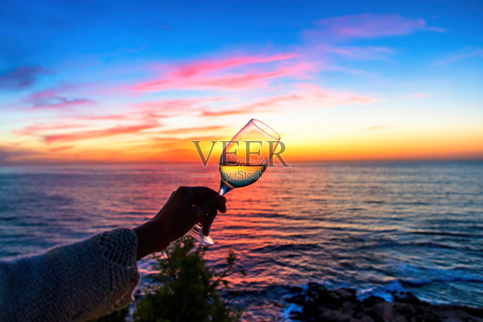 夕阳西下时，一杯白葡萄酒继续着大海的运动，在一个光、色和影的完美游戏中照片摄影图片