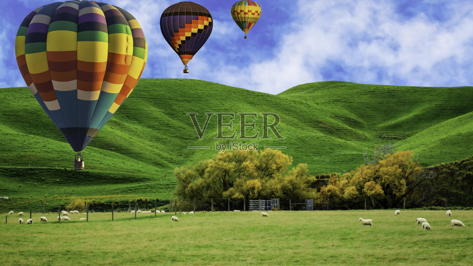 美丽的颜色的热气球飞过纽西兰的山丘照片摄影图片