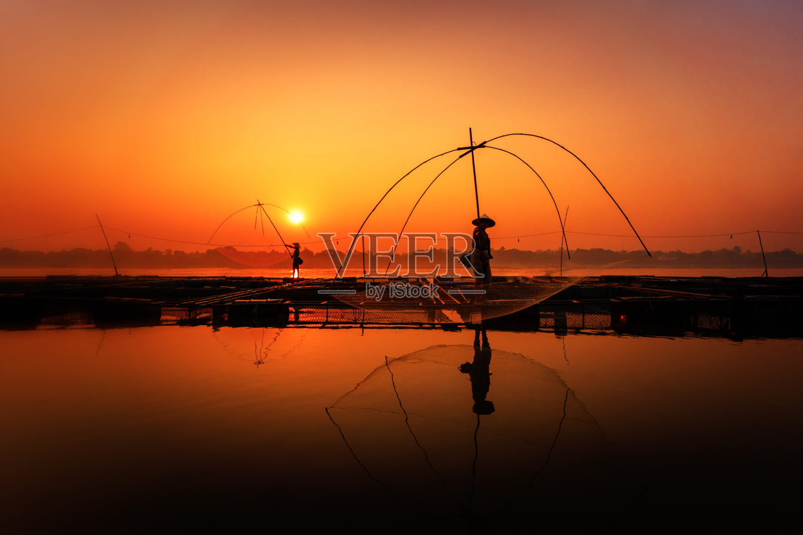 亚洲男人在湄公河上用渔网捕鱼。湄公河上，渔民们用漂浮的笼子饲养尼罗河罗非鱼。泰国廊开。照片摄影图片