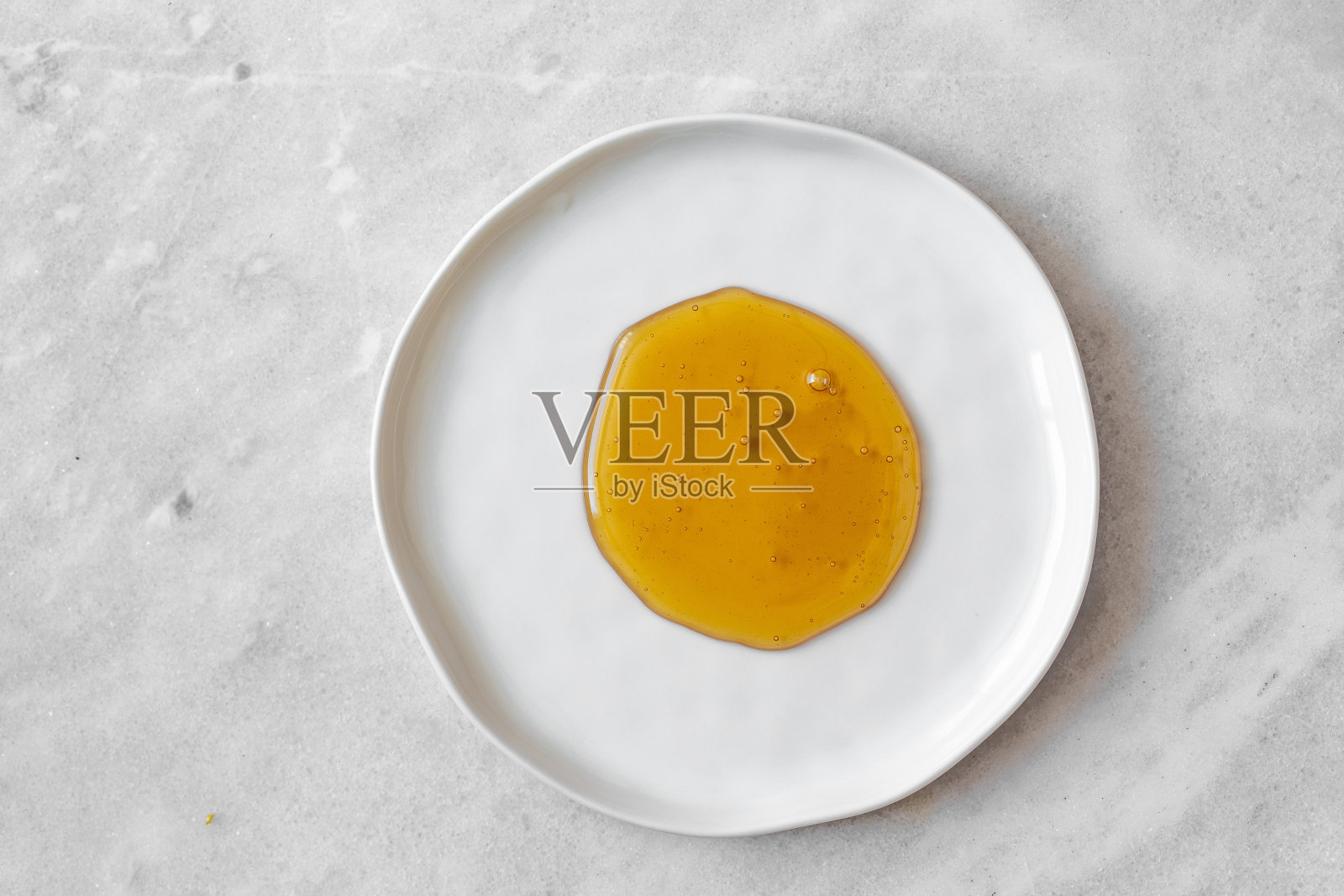 蜂蜜滴在白色盘子上，放置在透明的背景上照片摄影图片