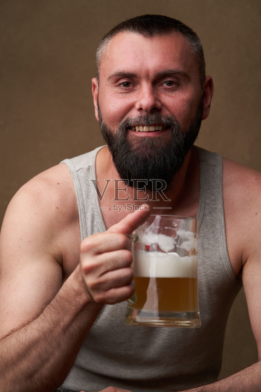 一个留着胡子的英俊男子的肖像，手里拿着一大杯啤酒照片摄影图片