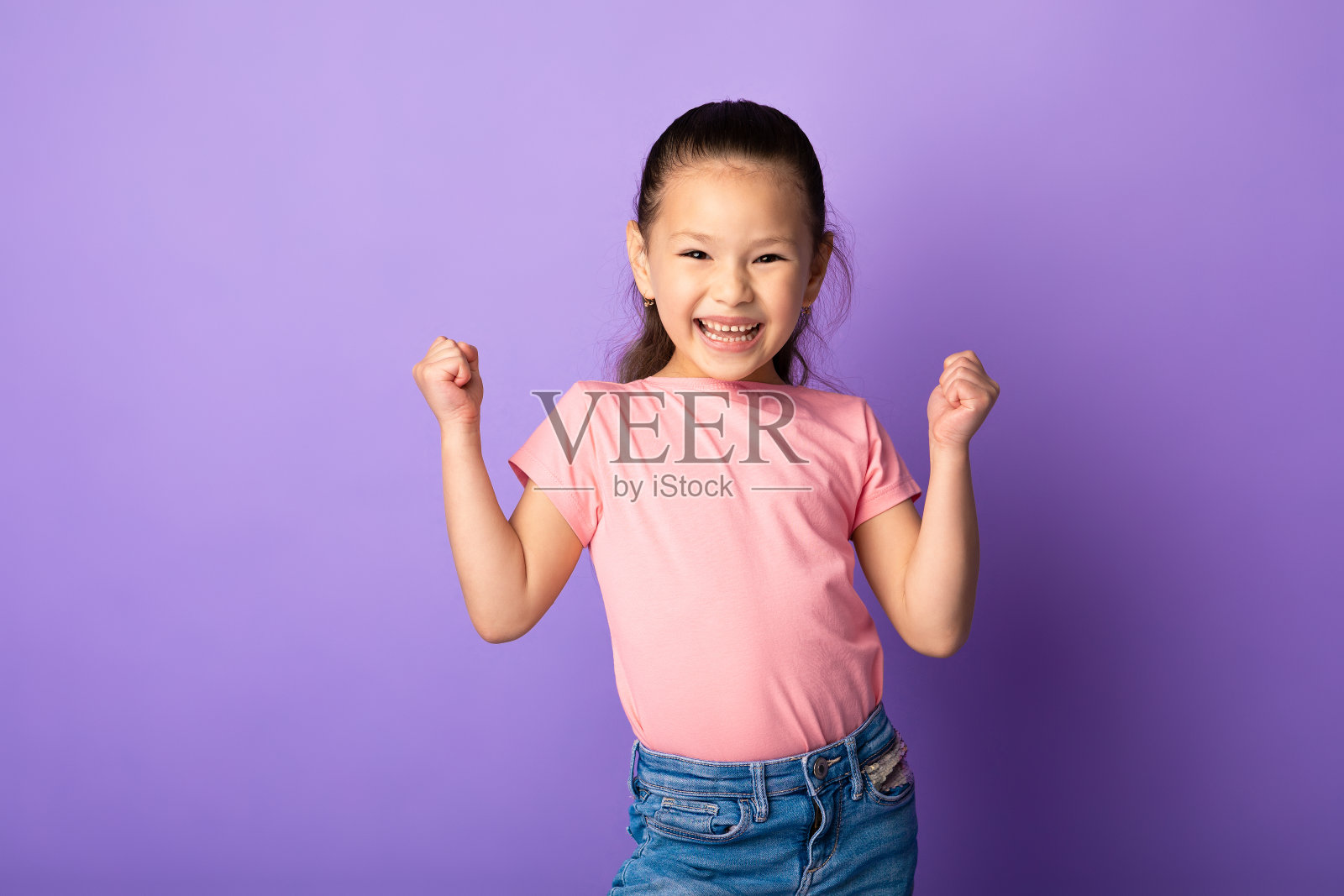 快乐的亚洲小女孩挥舞着拳头，做着胜利者的手势照片摄影图片