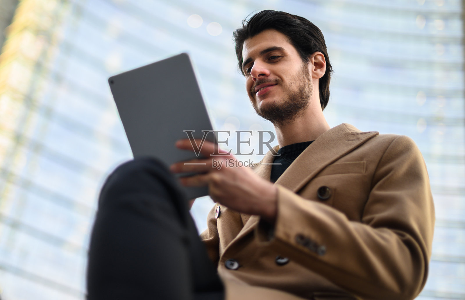 英俊的年轻人在户外的长椅上使用数码平板电脑照片摄影图片