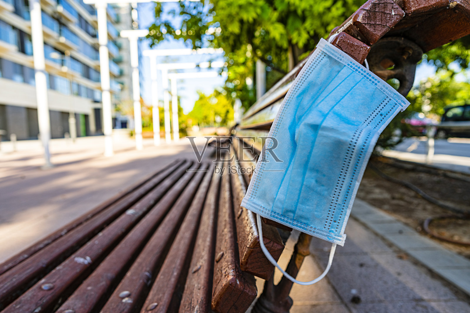 废弃在城市公共长椅上的肮脏用过的医用口罩照片摄影图片