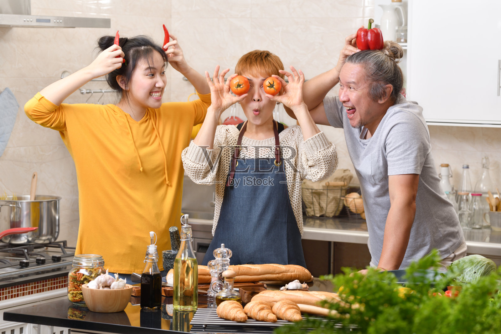 快乐的家庭，妈妈，爸爸和女儿在厨房做饭，一起做健康的食物，感觉有趣，做鬼脸照片摄影图片