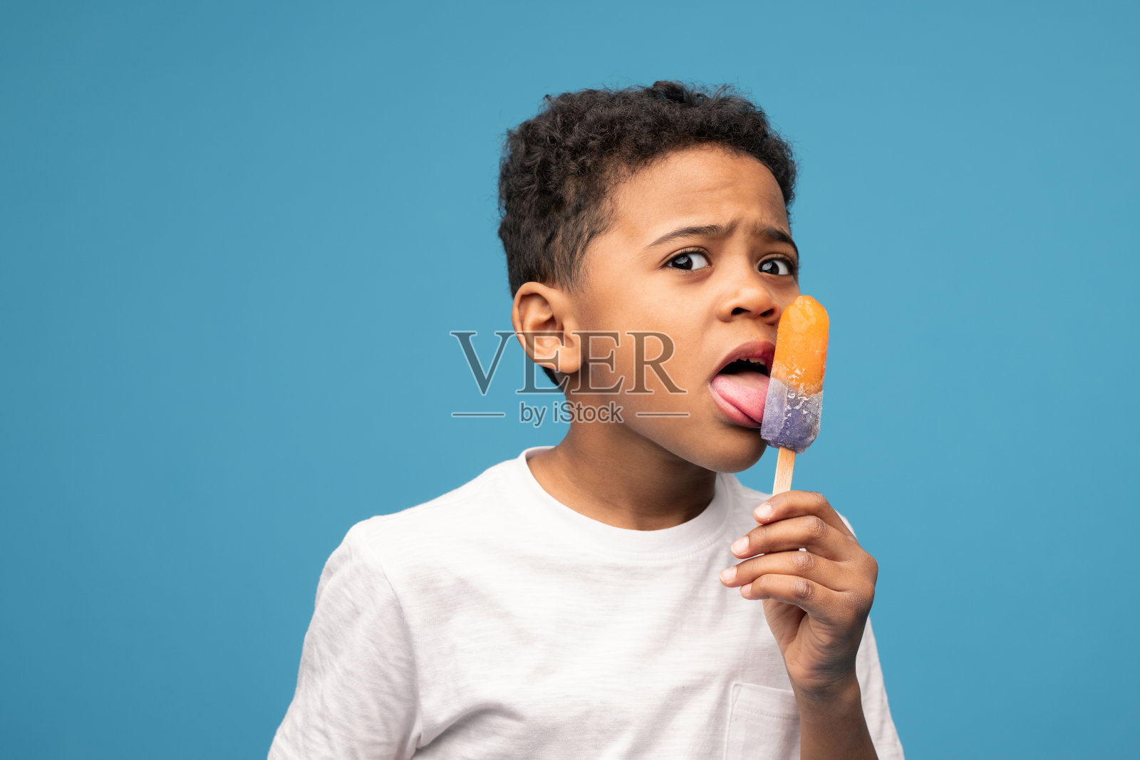 非洲血统的小男孩舔着橙汁味的冰淇淋照片摄影图片