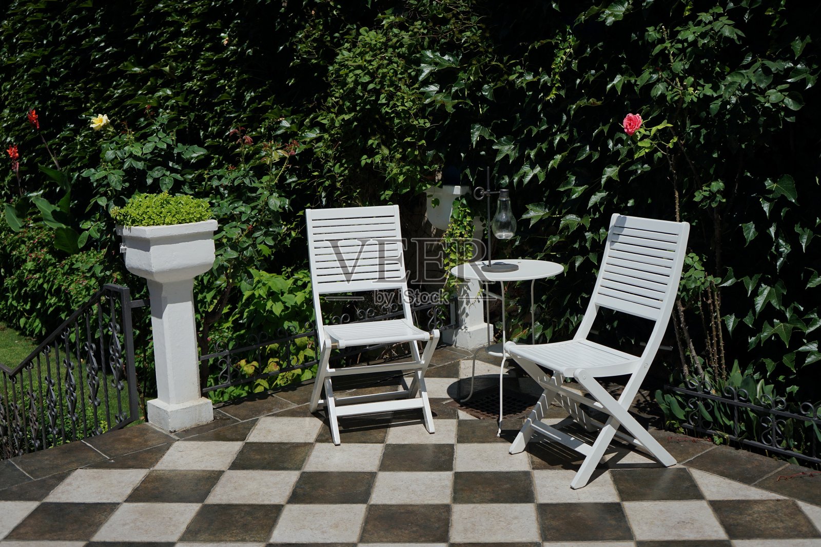 两张白色的椅子和桌子放在院子的露台上照片摄影图片