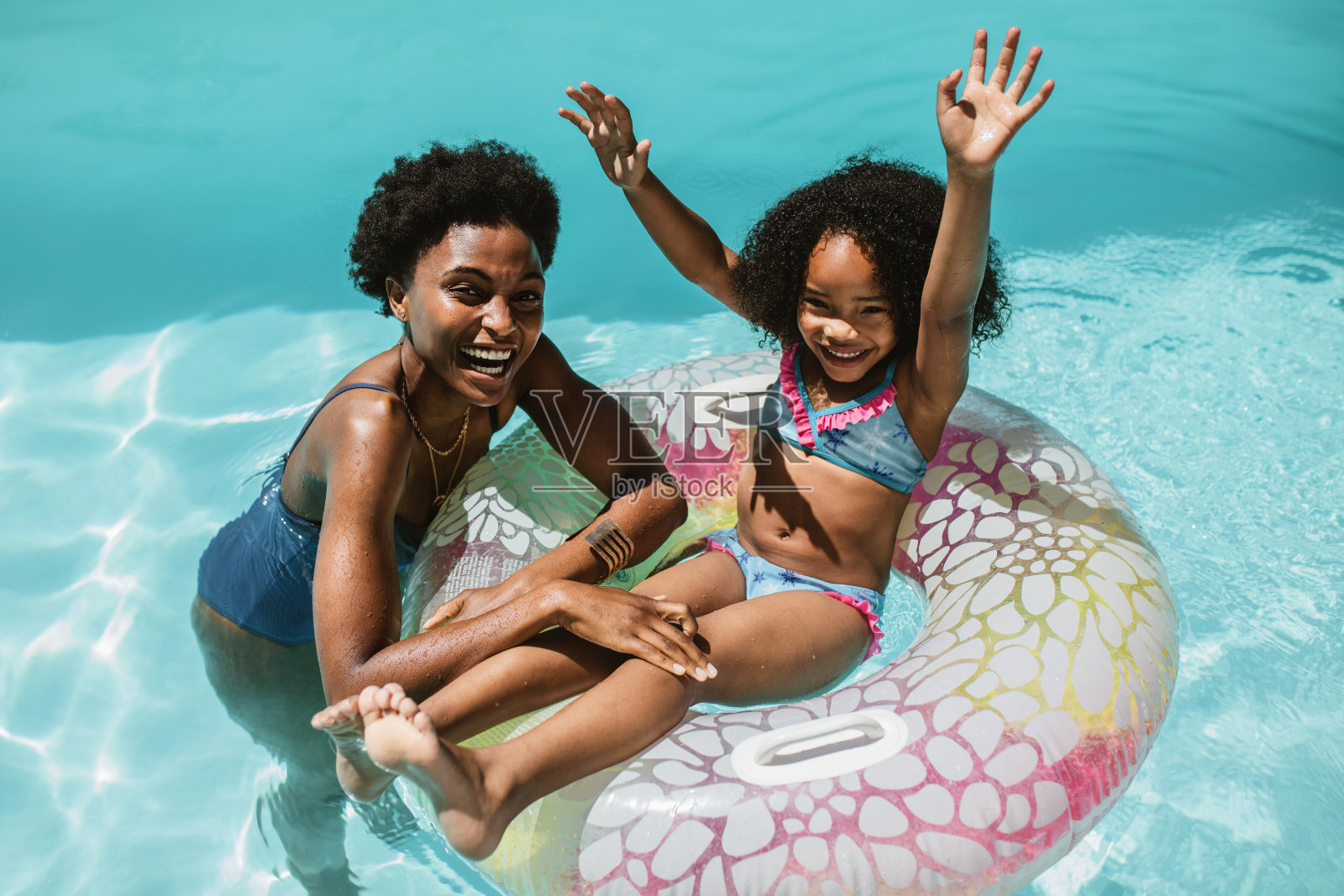 母亲和女儿在游泳池里享受暑假照片摄影图片