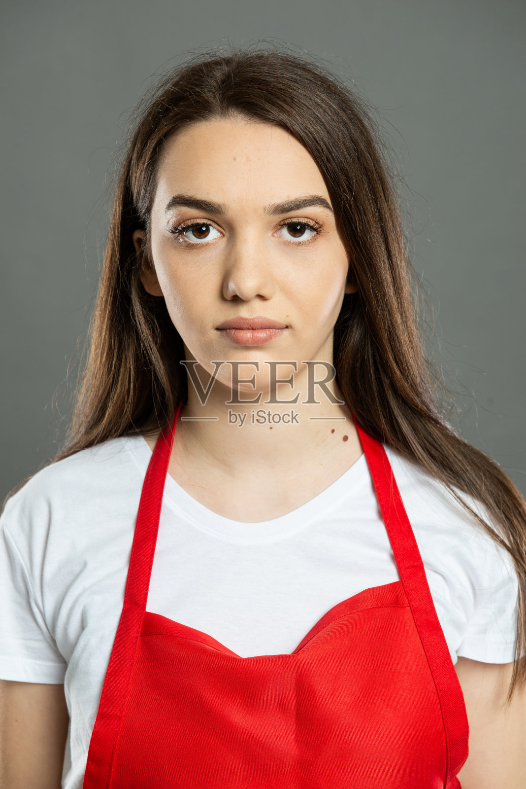 年轻迷人的女超市员工穿着红色围裙的肖像照片摄影图片