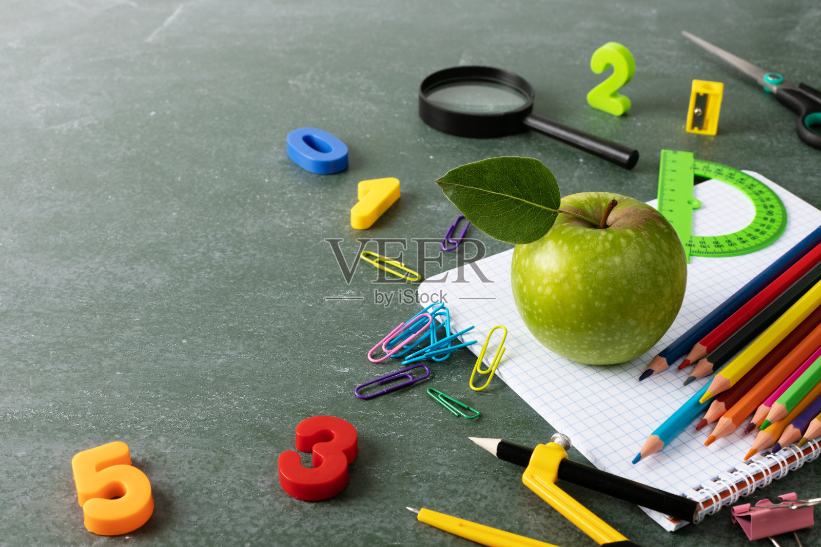 回归学校和教育理念，用五颜六色的文具和绿苹果在黑板上。照片摄影图片