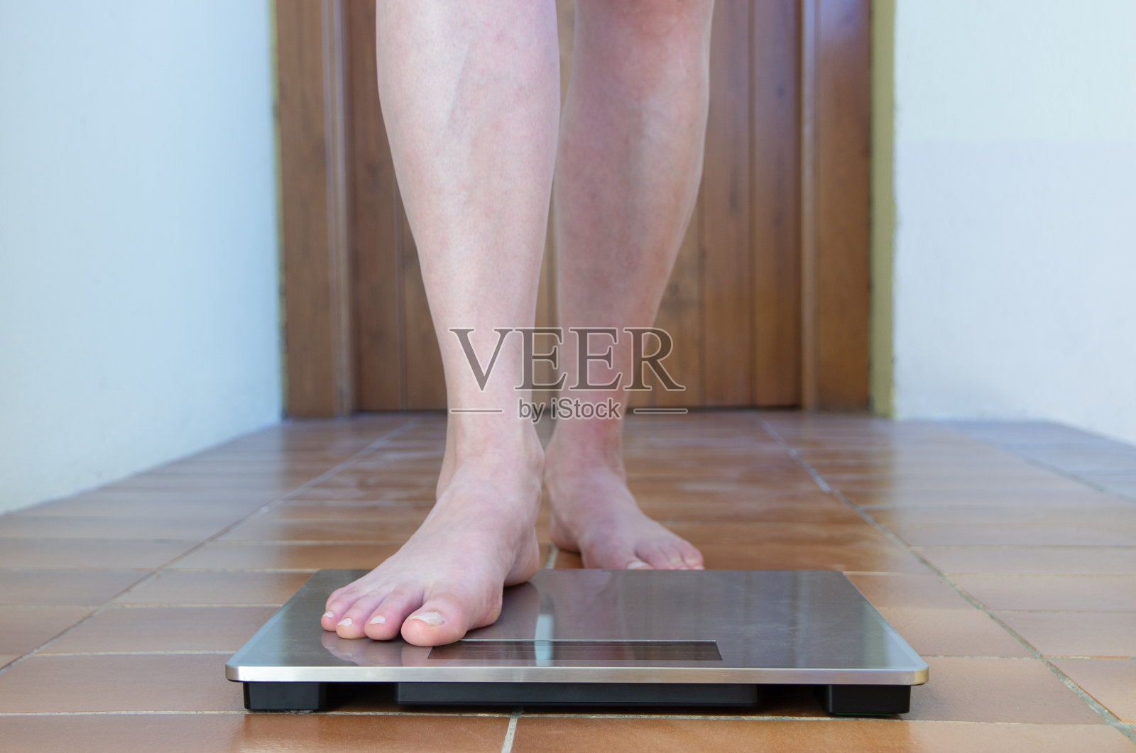 女人鳞片。女性踩在体重秤上。脚测量体重或超重，近处。腿检查体重照片摄影图片