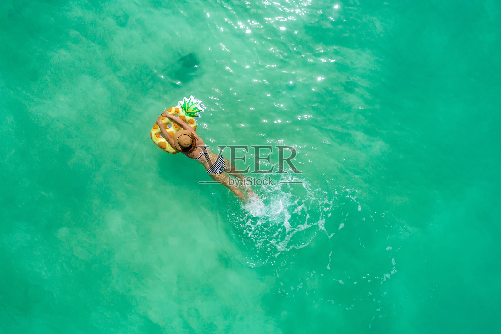 夏日时尚概念-晒黑女孩戴着太阳帽在沙滩上的白色沙滩上从上面拍摄。无人机俯视图。航拍的苗条女子躺在马尔代夫的海滩上晒太阳。照片摄影图片