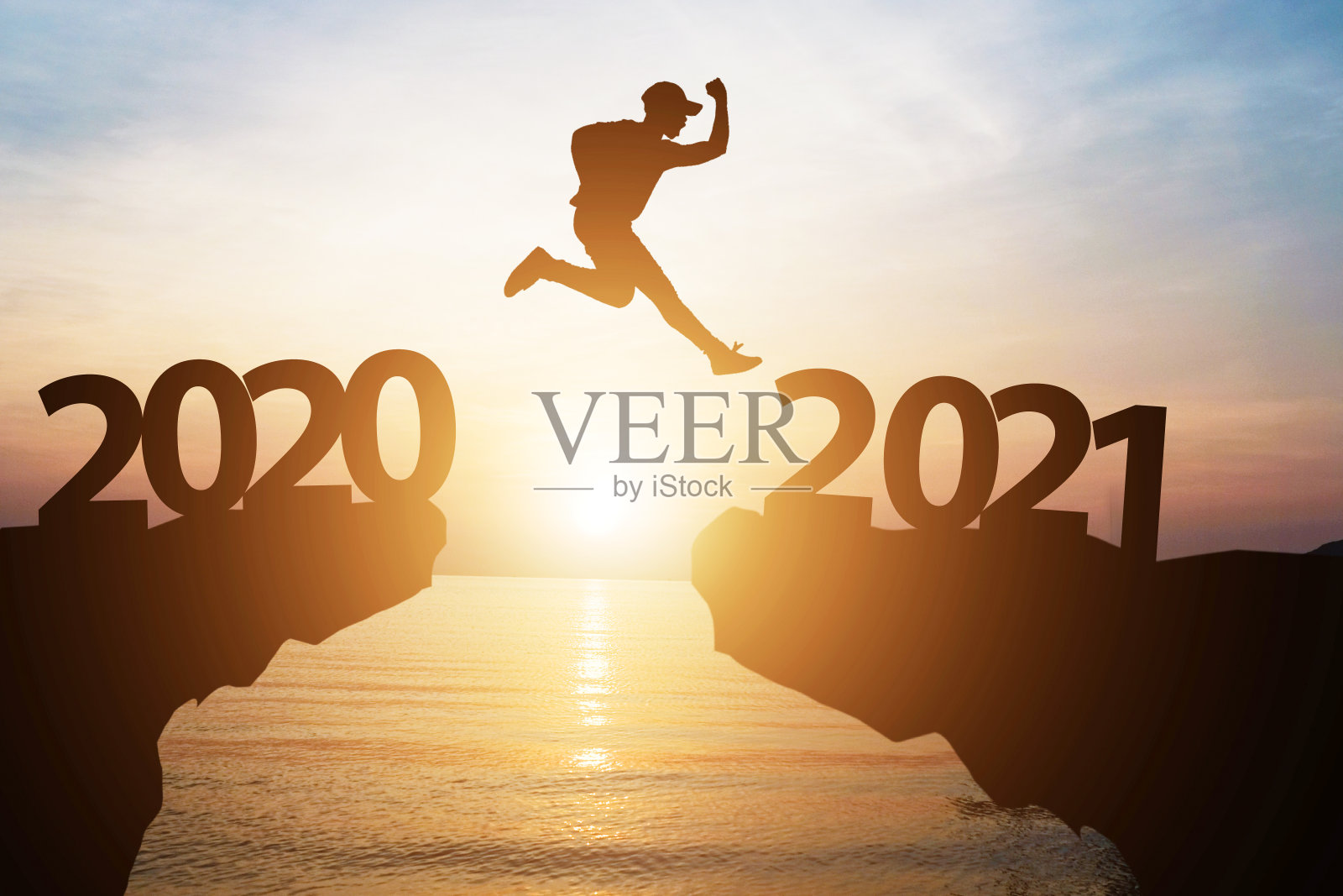 剪影男子从2020年跳到2021年，在阳光下的悬崖上改变，迎接新的一年。照片摄影图片