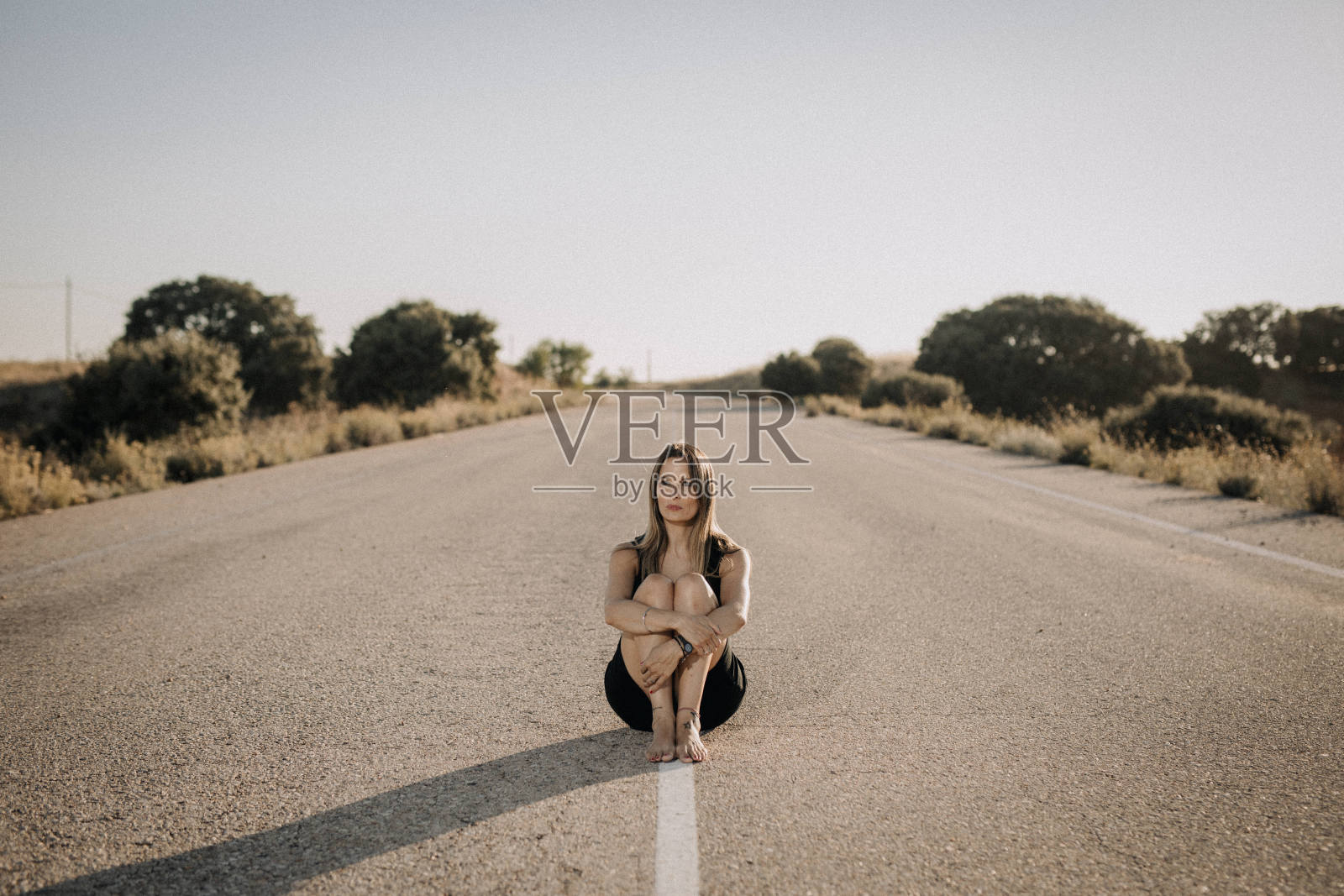 一个穿黑衣服的女人坐在空旷的路上照片摄影图片