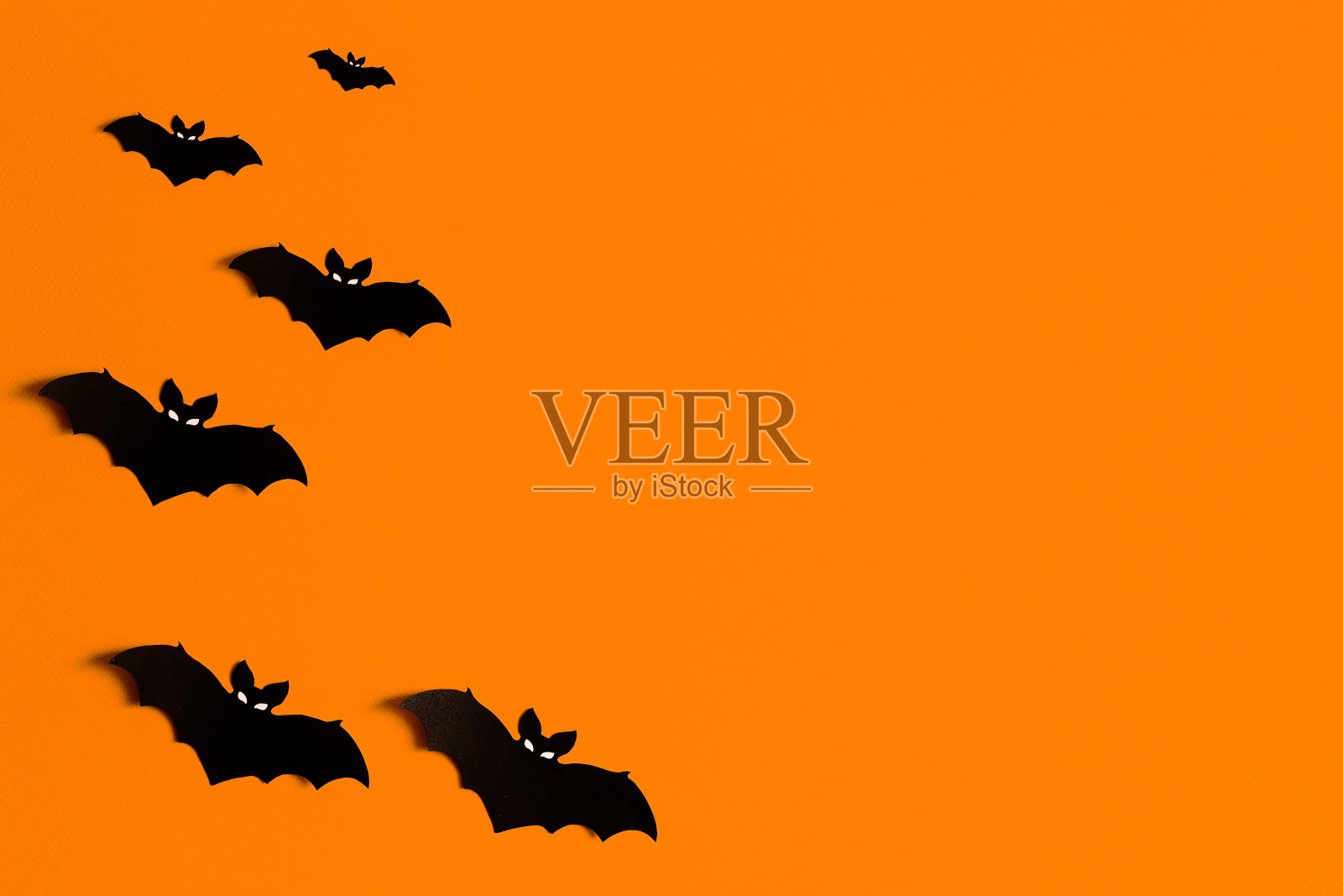 橙色的背景与一群黑色的纸蝙蝠的万圣节，黑色的纸蝙蝠的轮廓在一个橙色的背景，万圣节的概念，copyspace，平面，俯视图，头顶插画图片素材