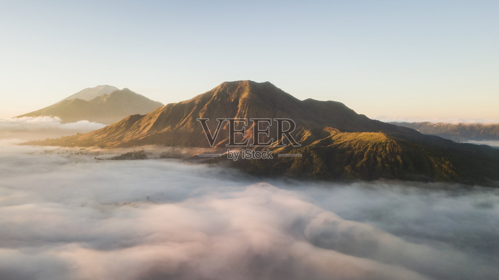 巴图尔火山在巴厘岛的鸟瞰图。美丽的日出和低低的云彩。全景。照片摄影图片