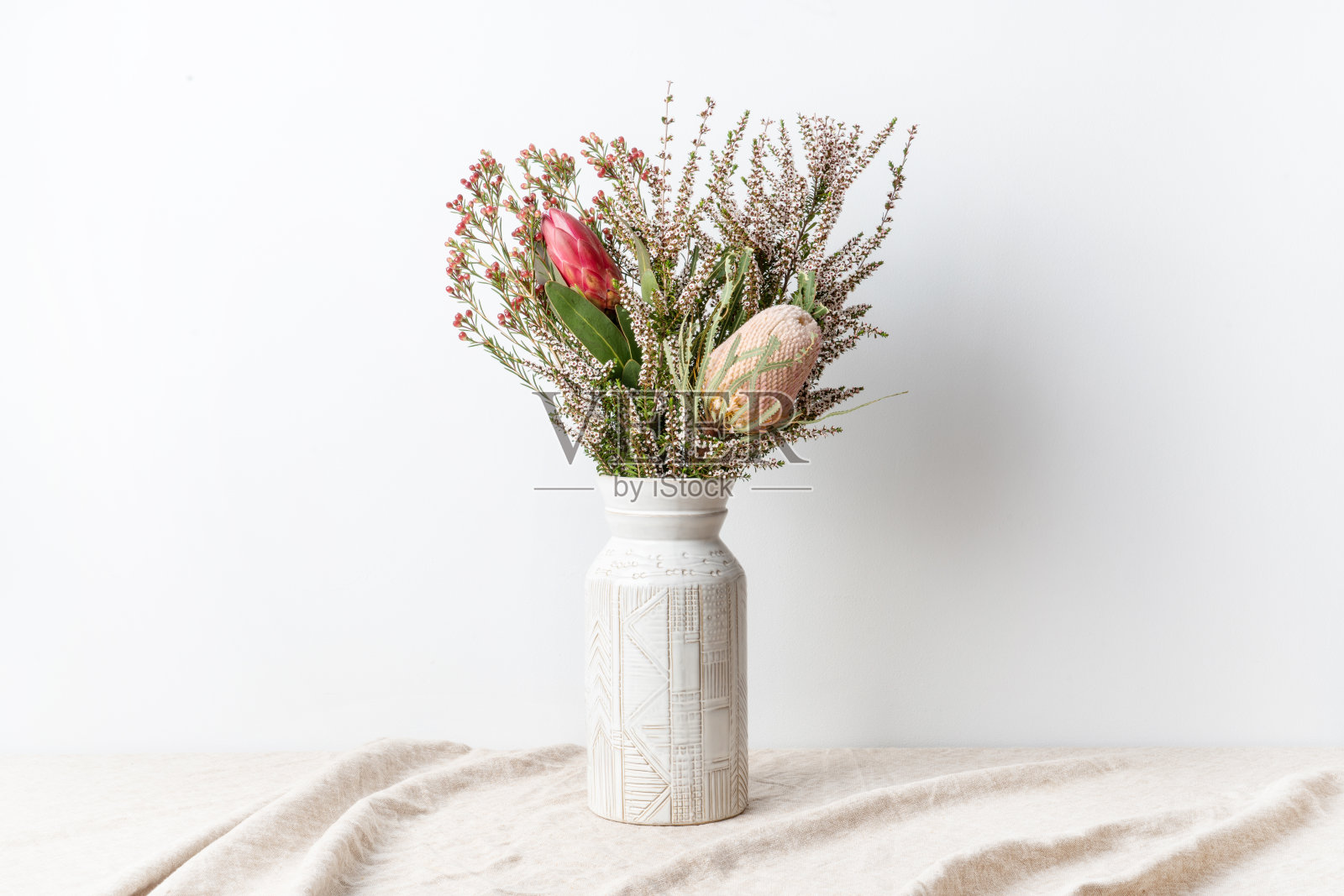 红色的protea，粉色的banksia和精致的白花，插在花瓶里。照片摄影图片
