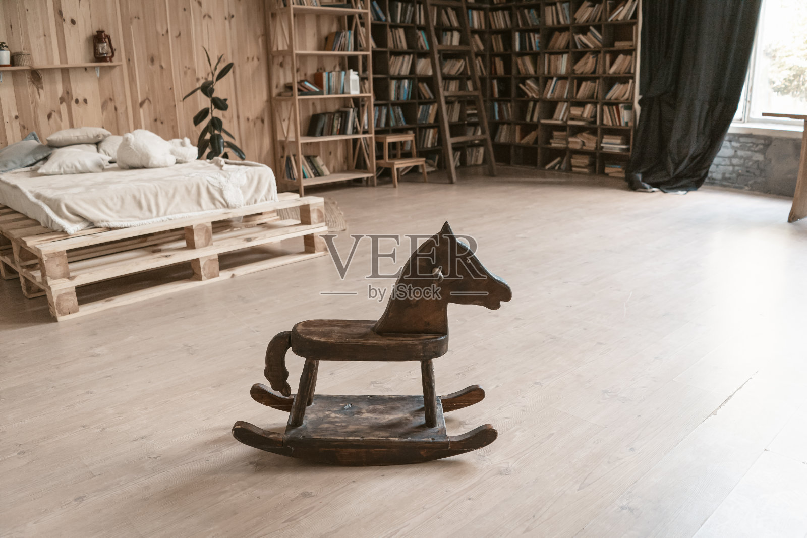 卧室在一个木制的室内。在前景是一个木马。背景是一张床和一个书架。高质量的照片照片摄影图片