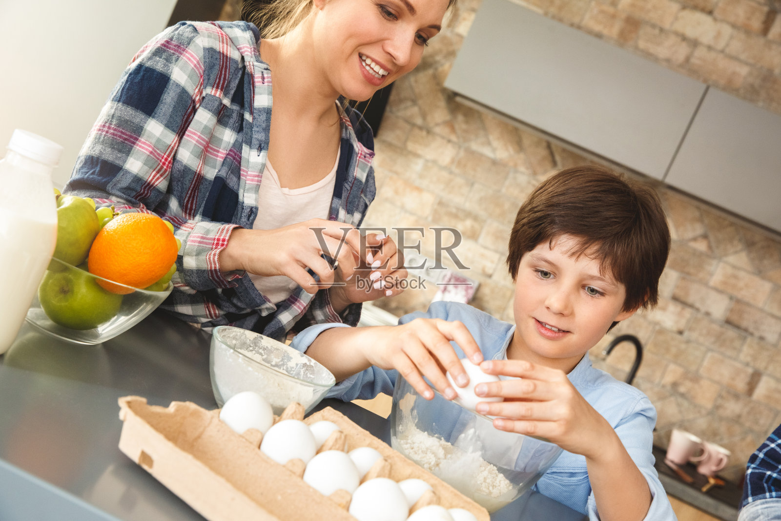 一家人站在厨房桌旁，母子一起欢快地吃着鸡蛋照片摄影图片