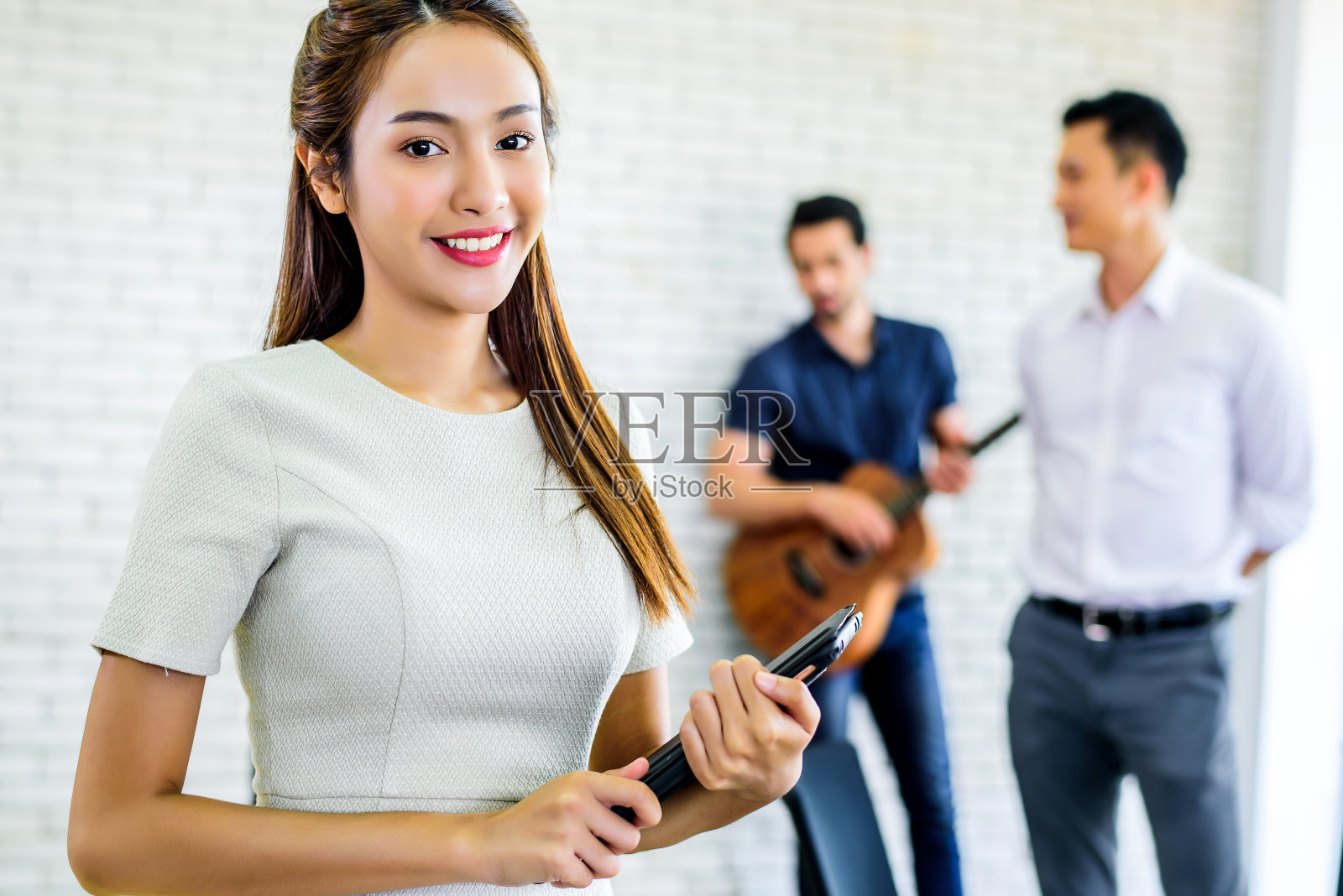 年轻自信的亚洲商业女性微笑着站在前面的业务团队会议或头脑风暴在办公室。团队会议和伙伴会议的工作理念。照片摄影图片