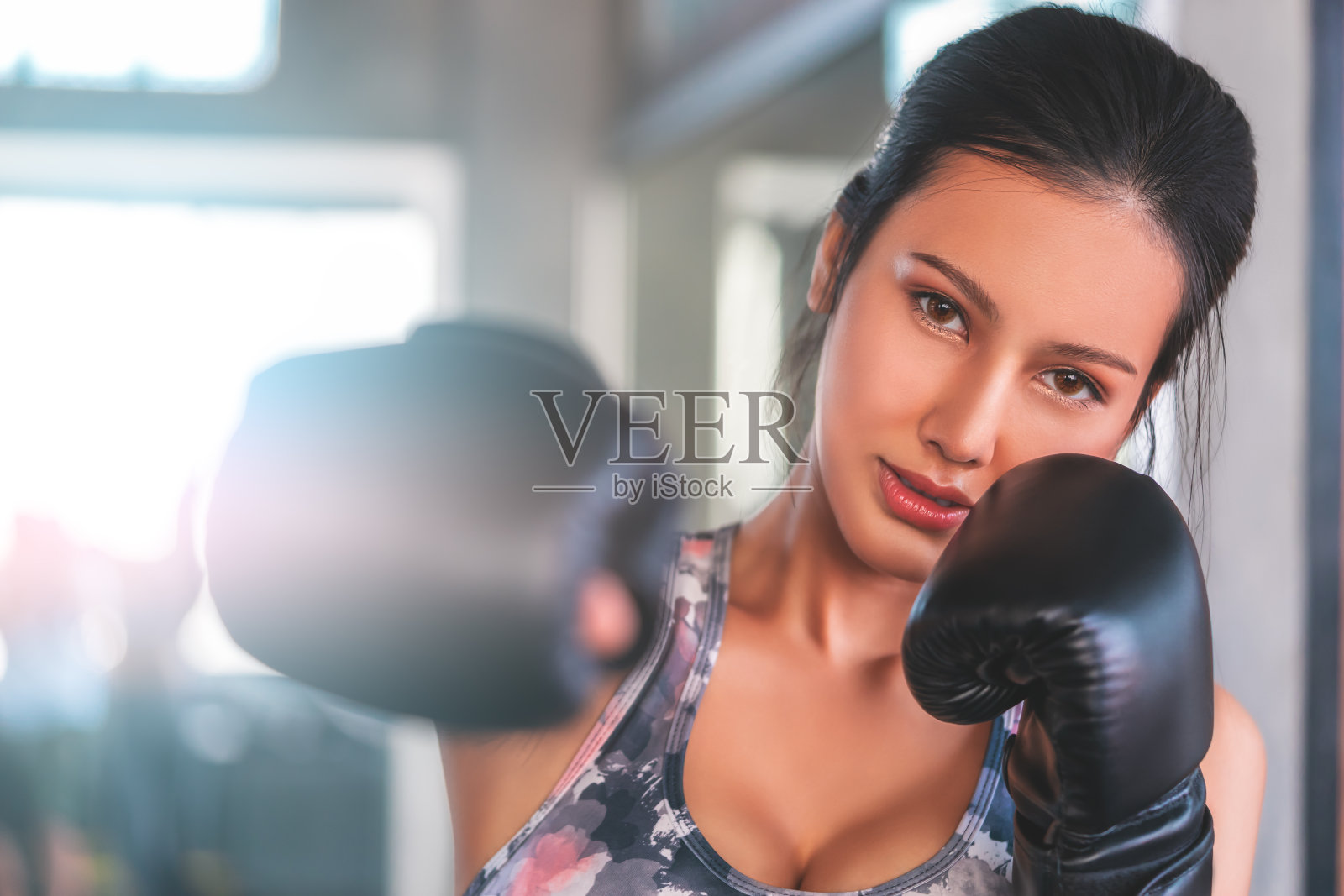 一名亚洲女子在室内健身房里对着镜头打拳击，以健身和健康的生活方式。照片摄影图片