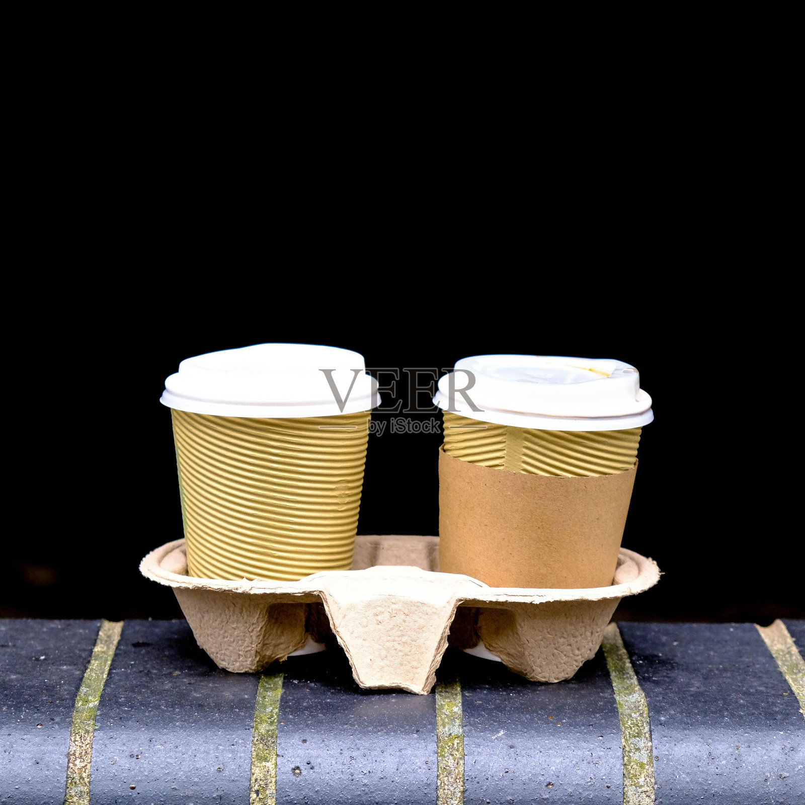 两个带盖子的棕色外卖硬纸板咖啡杯放在砖墙上照片摄影图片