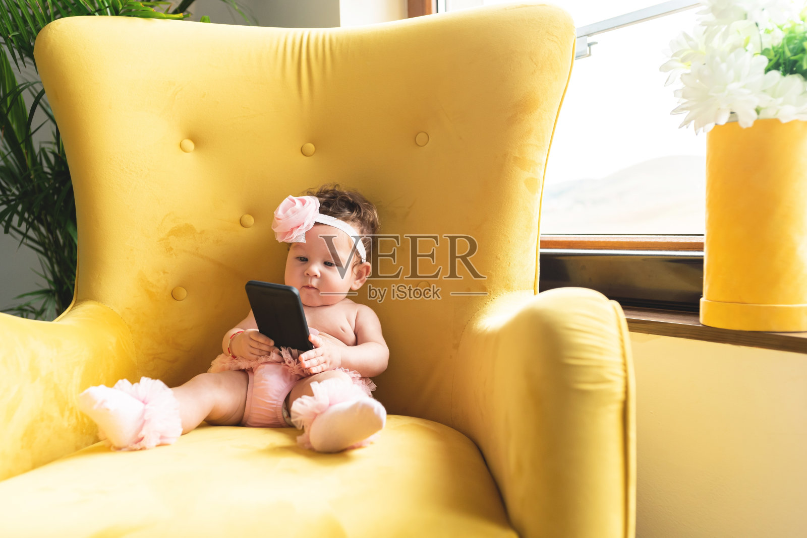 女婴在家里的扶手椅上使用手机照片摄影图片