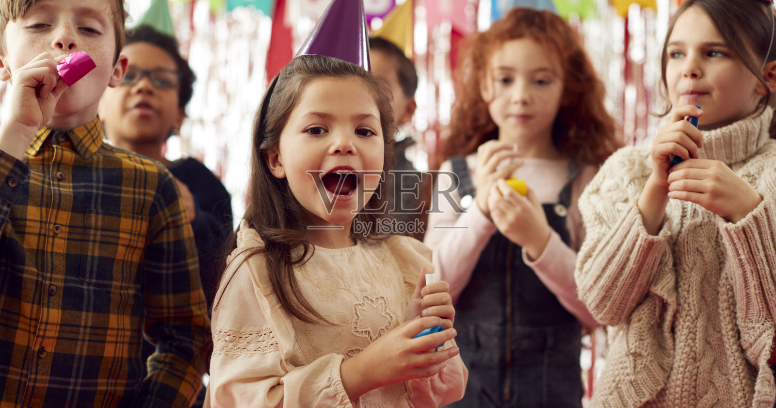 一群孩子在生日派对上用纸帽子和吹风机庆祝照片摄影图片