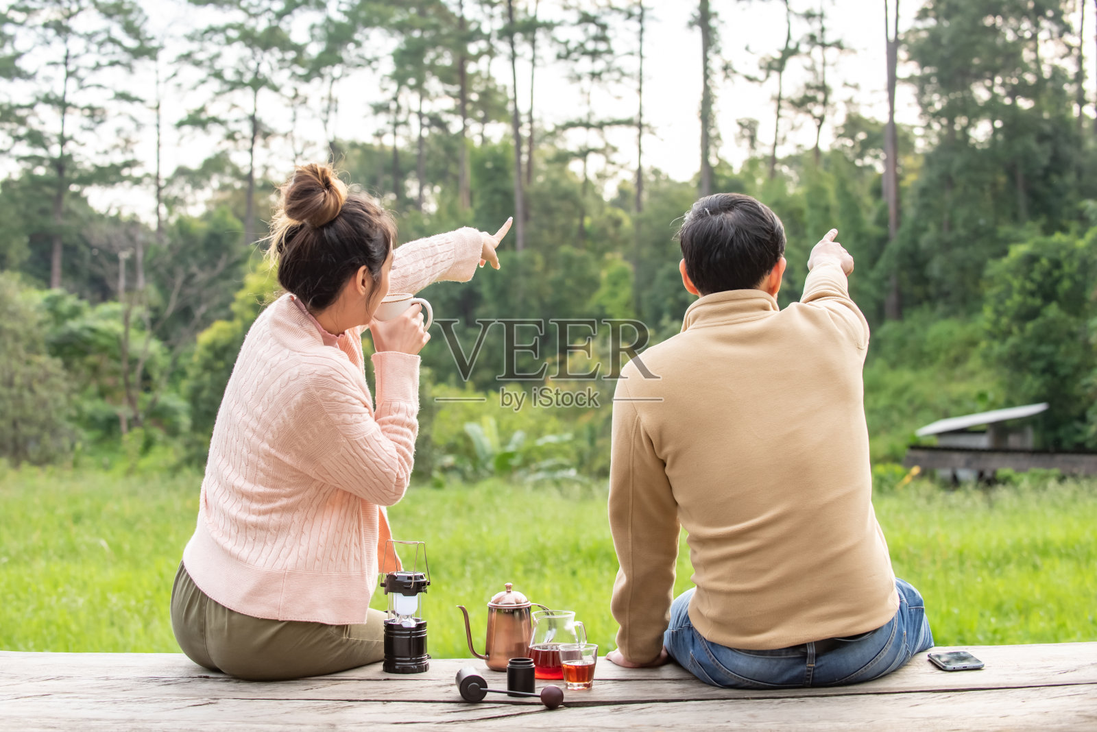 亚洲的一对男女游客坐在户外阳台在山区度假，喝一杯手滴咖啡与看美丽的自然在秋天的早晨。夫妻放松，享受户外生活方式和假日旅游假期。照片摄影图片